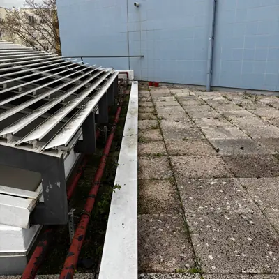 Tubagem vermelha enferrujada ao longo do murete, por baixo das grelhas de ventilação