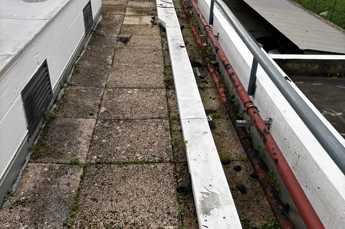 Tubagem de aço enferrujada a correr ao longo do murete de uma cobertura de edifício